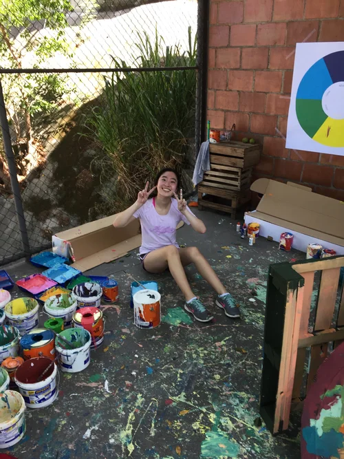 Student sitting among paint cans during an outreach art activity